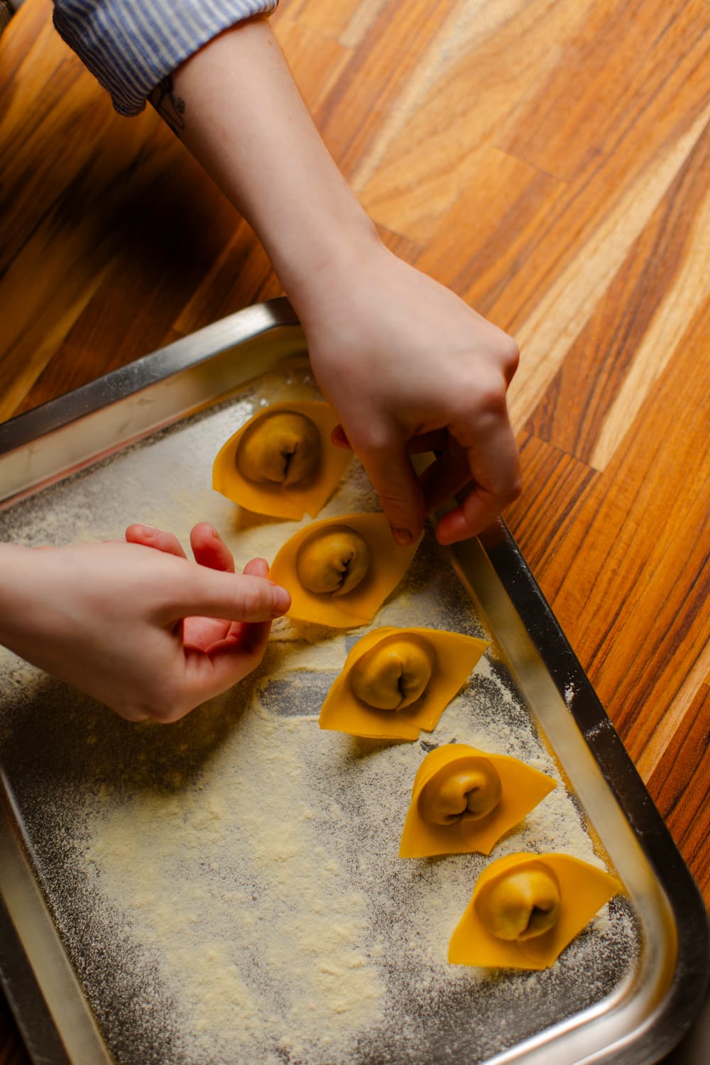 Tortelli frescos alinhados em bandeja sobre bancada